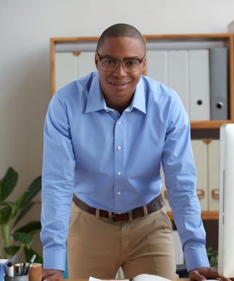 Portrait of Black smiling businessman standing at his workplace